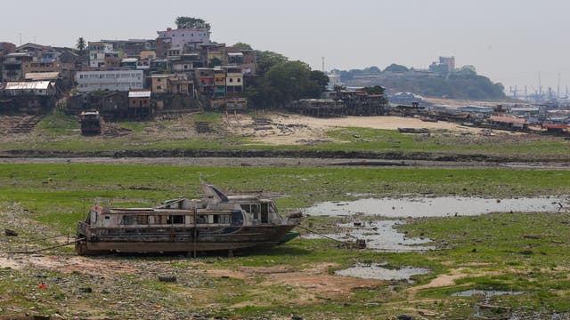Ein Schiff liegt im trockengefallenen Hafenbecken, im Hintergrund Gebäude.