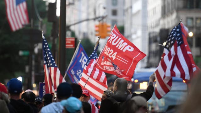 Menschen mit Flaggen der USA und Fahnen mit der Aufschrift "Trump 2024" in einer Straße von New York
