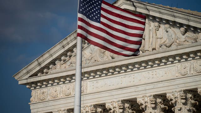 Die amerikanische Flagge weht vor einem blauen Himmel an einem Fahnenmast vor dem Supreme Court