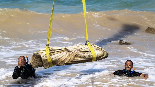 Taucher im Meer bergen eine antike Statue mit Hilfe von Hebegurten. 