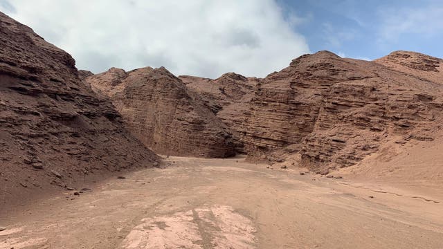 Rötliche Gesteinsformation in einer Wüste.