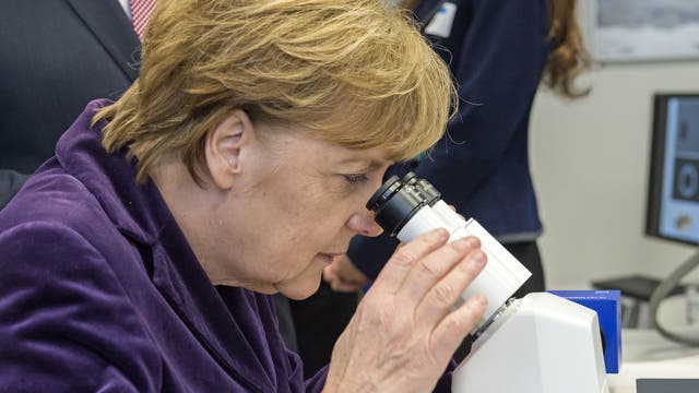 Bundeskanzlerin Angela Merkel blickt durch ein Mikroskop