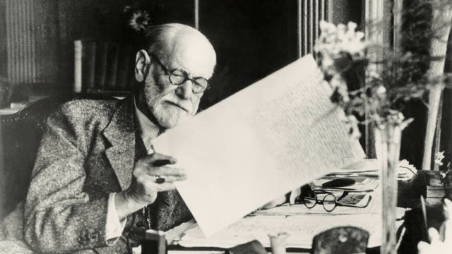 Freud liest einen Briefbogen mit Stift in der Hand