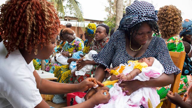 Ein Baby auf dem Arm der Mutter wird von einer Gesundheitsarbeiterin geimpft