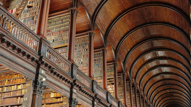 In einer altehrwürdigen dunkel getäfelten Bibliothek sind auf zwei Etagen unzählige Buchrücken zu erkennen