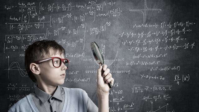 Junge mit Lupe vor vollgeschriebener Tafel mit Matheformeln