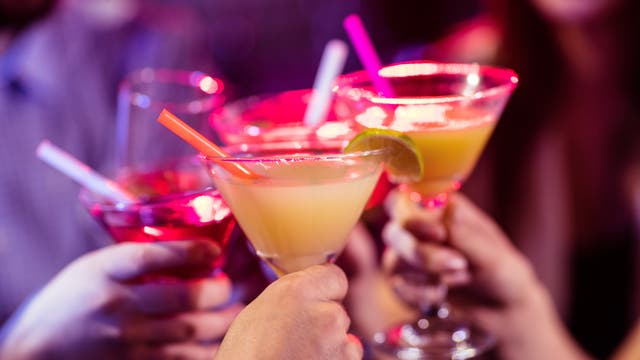 Freunde stoßen in einer Bar mit Cocktails an 