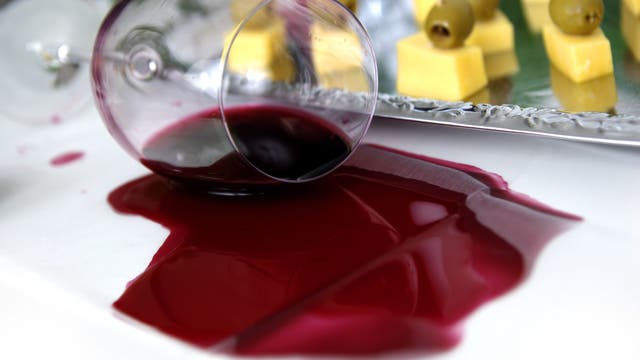 Rotwein läuft aus einem umgefallenen Weinglas.