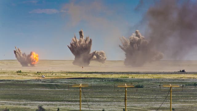 Drei Explosionen durch Fliegerbomben auf einem Truppenübungsplatz. Bei der Verbrennung von TNT entsteht viel Ruß, so dass die Rauchwolken dunkel sind.