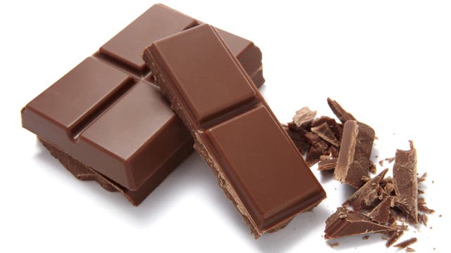 Zwei Stücke Schokolade und einige Schokospäne daneben vor weißem Hintergrund