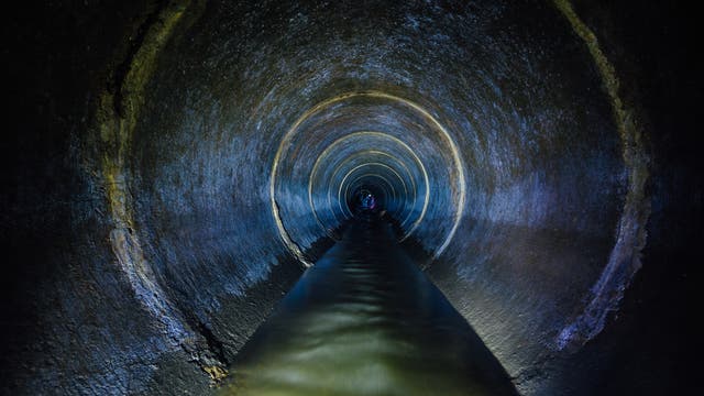 Ein Blick in einen lang gestreckten, dunklen Kanalisationstunnel