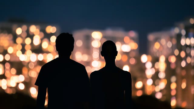 Silhouette eines Paares bei Nacht vor Großstadtlichtern