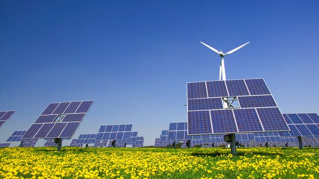 Windrad und Solarzellen ergänzen sich auf einer Wiese