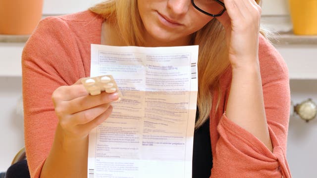 Eine Frau liest mit ernster Miene einen Beipackzettel