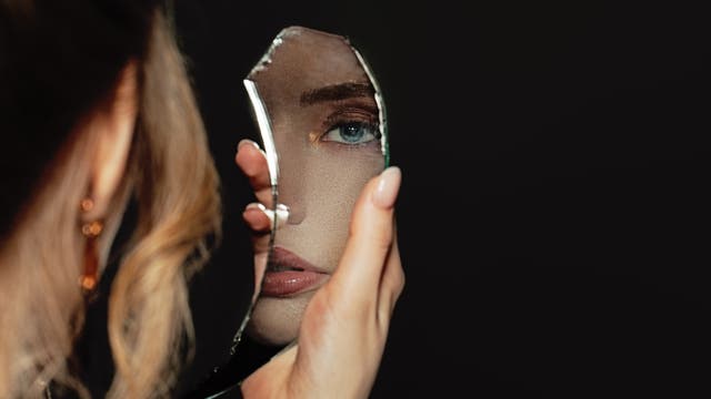 Frau schaut in zerbrochenen Spiegel