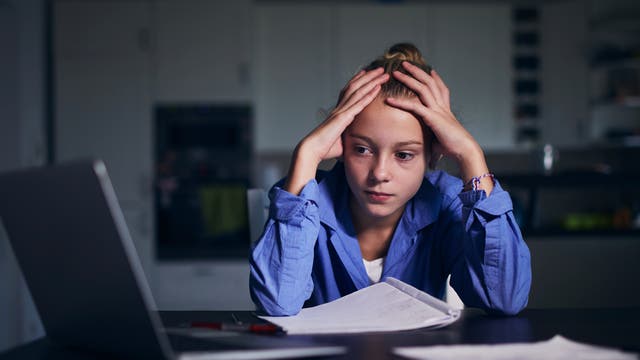 Junge Frau sitzt vor dem Computer und hadert mit sich