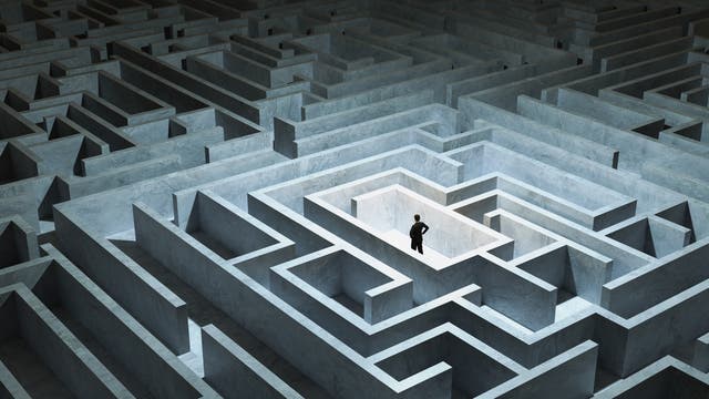 Ein Mann steht inmitten eines Labyrinths und überlegt, wie er herauskommt.