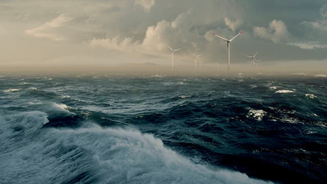 Stürmische Meereslandschaft mit mehreren Windkraftanlagen im Hintergrund. Die Windräder ragen aus dem Wasser und sind von dramatischen Wolken umgeben. Die Szene vermittelt eine Atmosphäre von erneuerbarer Energiegewinnung in rauen Wetterbedingungen.
