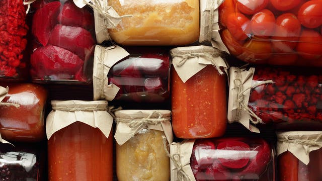 Eine Sammlung von Einmachgläsern, die verschiedene eingelegte und konservierte Lebensmittel enthalten. 