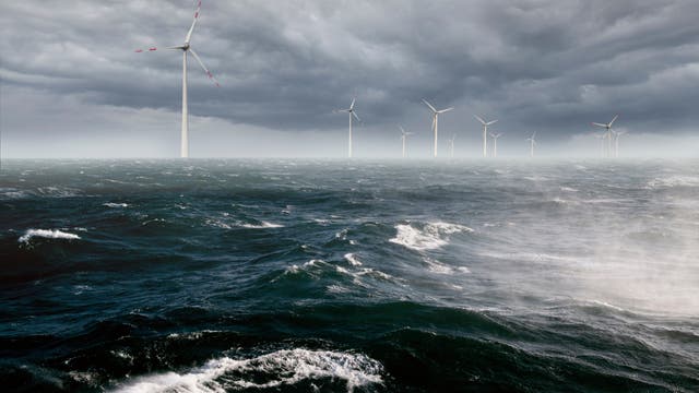 Offshore-Windpark bei stürmischem Wetter. Mehrere Windturbinen stehen im Meer unter einem dunkel und bedrohlich wirkenden bewölkten Himmel. Die Wellen sind hoch und der Wind stark.