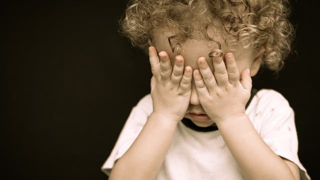 Lob kann auch verunsichern – ein Kleinkind schlägt die Hände vor das Gesicht