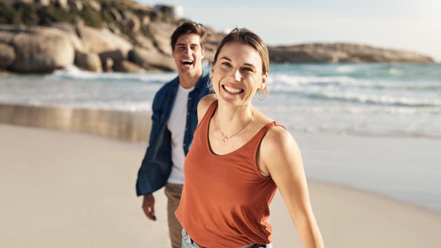 Lächelnde Frau am Strand mit einem etwas jüngeren Mann