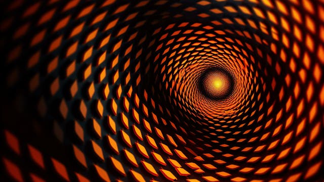 Blick in eine Röhre aus einem Gitter mit Rhombenförmigen Löchern, durch die orange-gelbes Licht fällt