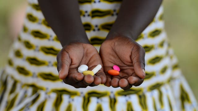 Ein afrikanisches Mädchen hält Tabletten in der Hand