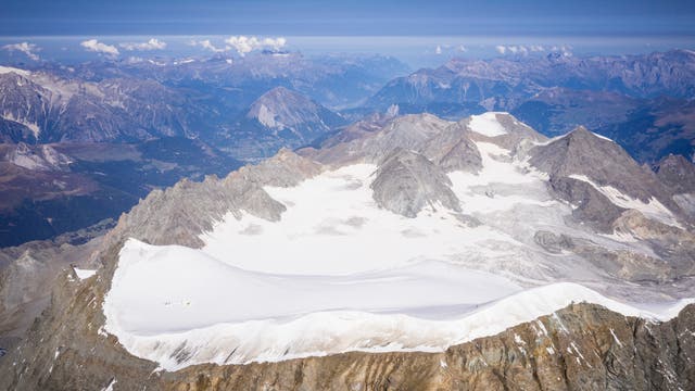Luftaufnahme des Alpengletschers am Grand Combin: ein gletscherbedeckter Gebirgsrücken, ringsrum weitere Berggipfel ohne Schnee und Eis