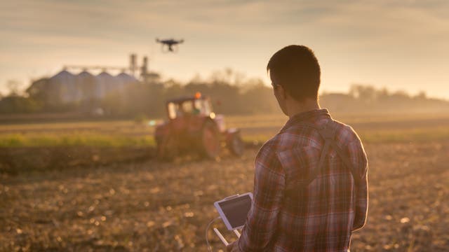 Landwirt überwacht mit Drohne und Tablet die Ernte