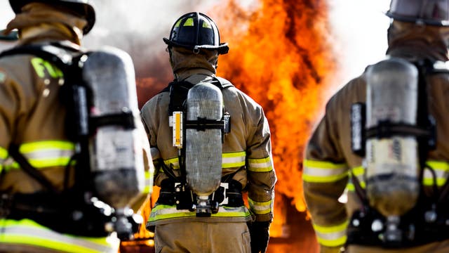 Feuerwehr im Einsatz von hinten vor Brand fotografiert