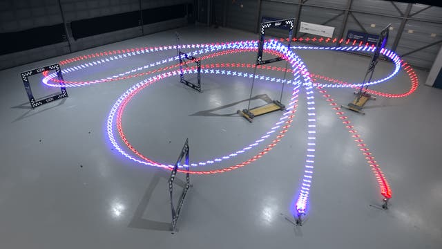 Leuchtende Spuren zweier Drohnen in einem Hindernisparcours zeigen die absolvierten Flugstrecken