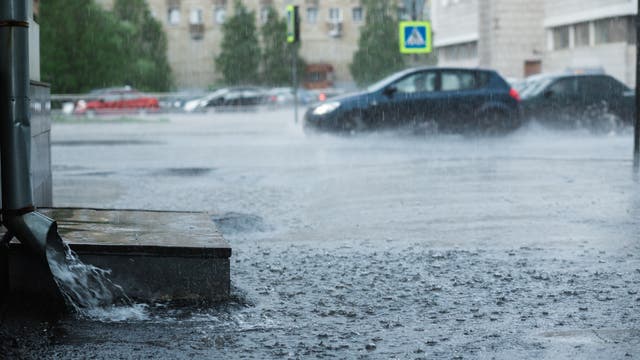 Überschwemmte Straße, im Vordergrund ein Hauseingang und ein Regenrohr