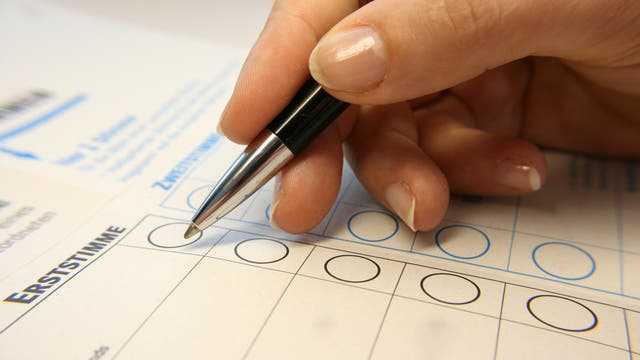 Eine Hand mit Stift kreuzt auf einem Wahlzettel für die Bundestagswahl ein Feld an.