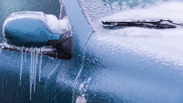 Eiskruste auf Außenspiegel und Scheibenwischer eines Autos