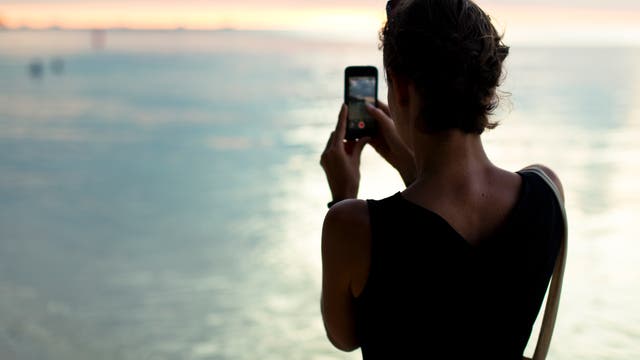 Frau macht Foto vom Sonnenuntergang