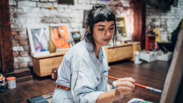 Junge Künstlerin malt in einem Atelier