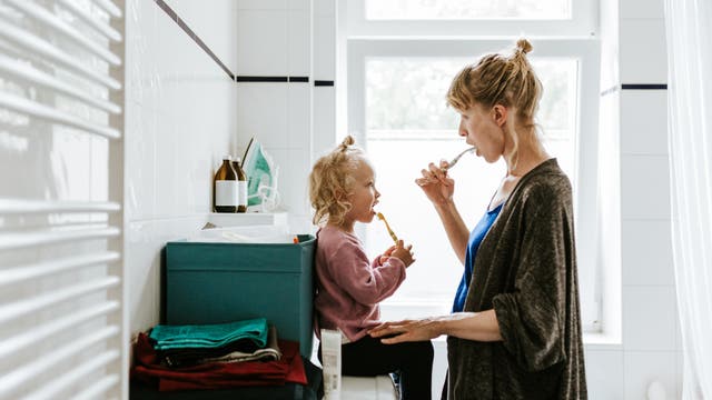 Mutter mit Kleinkind, die gemeinsam Zähne putzen