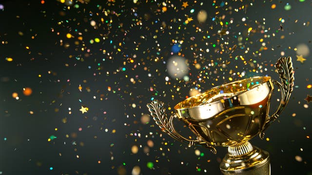 Über einem goldenen Pokal fliegt glitzerndes Konfetti