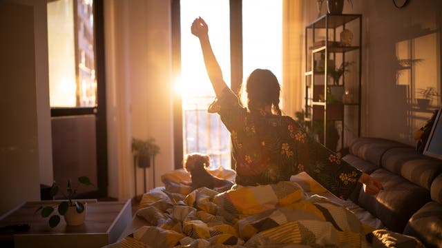 Eine Frau wacht bei Sonnenaufgang auf. Wobei der Sonnenstand darauf hindeutet, dass sie sich beim tatsächlichen Sonnenaufgang noch mal ein gutes halbes Stündchen hingelegt hat. Aber wir wollen nicht kleinlich sein.