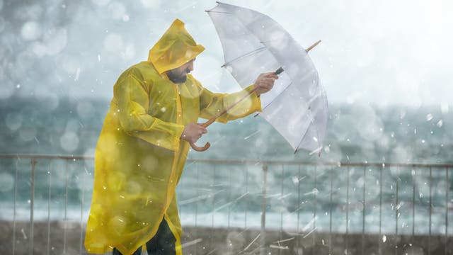 Ein Mann mit gelbem Mantel steht im Regen