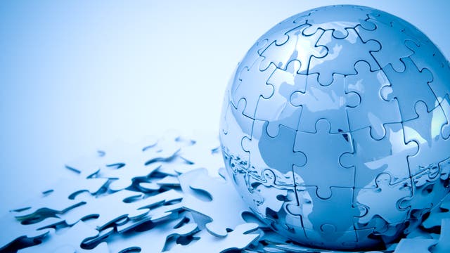 Ein kugelförmiges Puzzle aus glänzenden, silbernen Teilen, das auf einem Haufen loser Puzzleteile liegt. Die Oberfläche reflektiert das Licht und erzeugt einen futuristischen Effekt. Es gibt keinen Text im Bild.