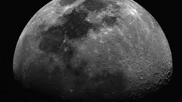 Eine detaillierte Nahaufnahme des Mondes, die seine Krater und dunklen Meere zeigt. Die Oberfläche ist klar sichtbar mit verschiedenen Schattierungen von Grau, die die topografischen Merkmale hervorheben. Der Hintergrund ist schwarz, was den Fokus auf den Mond verstärkt.
