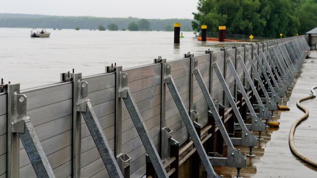 Eine mobile Sperre aus Stahlwänden verhindert, dass Wasser in ein Wohngebiet fließt.