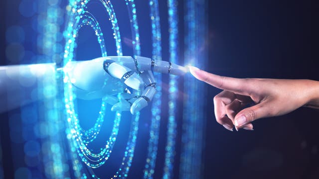 Eine menschliche Hand und eine Roboterhand berühren sich mit den Fingerspitzen vor einem Hintergrund aus leuchtenden, blauen Lichtkreisen. Die Szene symbolisiert die Verbindung zwischen Mensch und Technologie.