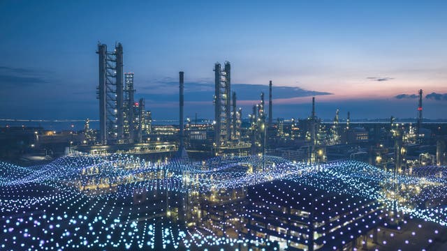 Industrieanlage bei Dämmerung mit mehreren hohen Türmen und Schornsteinen, die sich gegen den Abendhimmel abheben. Im Vordergrund sind leuchtende, wellenförmige Muster zu sehen, die möglicherweise digitale Datenströme symbolisieren. Die Szene vermittelt eine Verbindung von industrieller Infrastruktur und moderner Technologie.