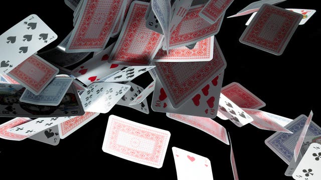 Ein Haufen klassischer Spielkarten fliegt vor einem schwarzen Hintergrund durch die Luft. Die Karten sind in verschiedenen Ausrichtungen sichtbar, mit Vorder- und Rückseiten, die unterschiedliche Farben und Muster zeigen. Einige Karten sind klar erkennbar. Die Szene vermittelt Bewegung und Dynamik.