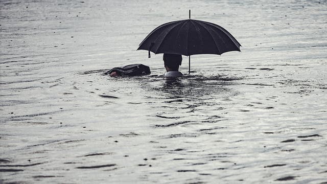 Mann mit Schirm im Wasser