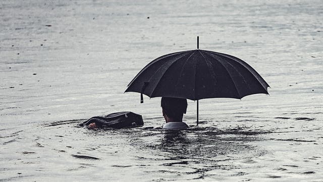 Mann mit Schirm in Wasser.