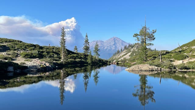 Eine Rauchwolke zieht von links an den Heart Lake in Kalifornien heran. Der See ist von Bergen und wenigen Bäumen umgeben.